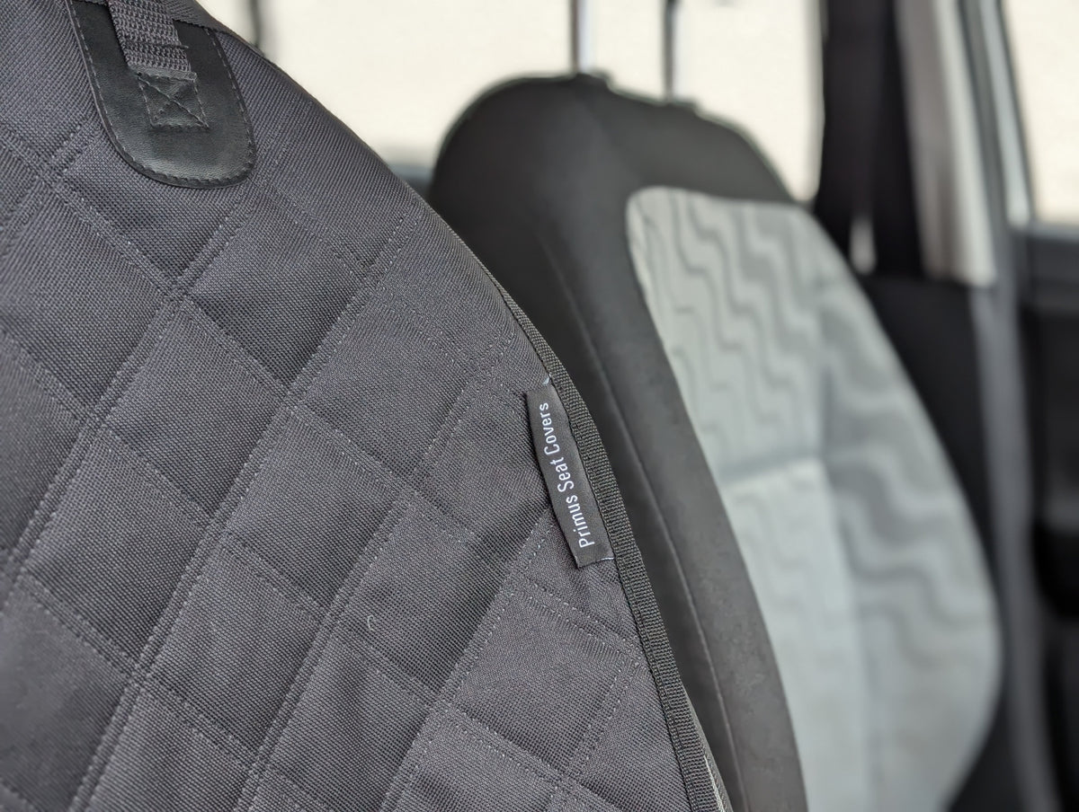 Dark gray quilted seat protector with small branded label on side seam