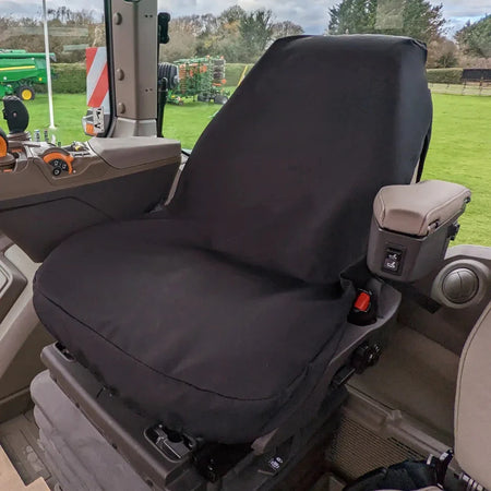 Black tractor seat cover fitted over seat and armrest, with side buckle cutouts
